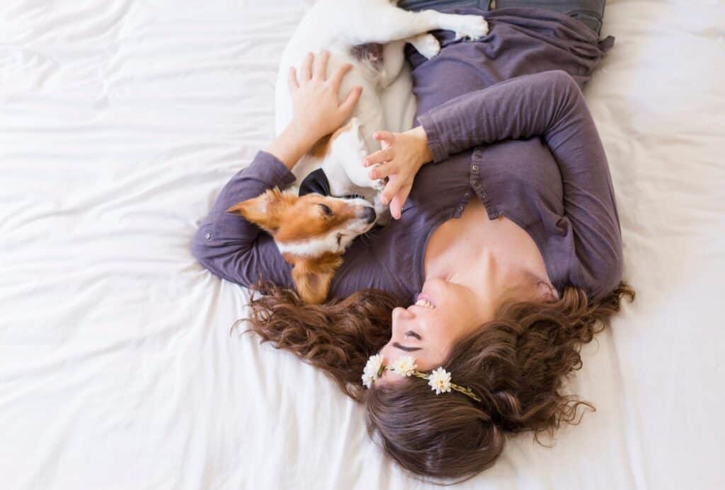 Top view of a young woman lying on bed with her cute small dog besides.
