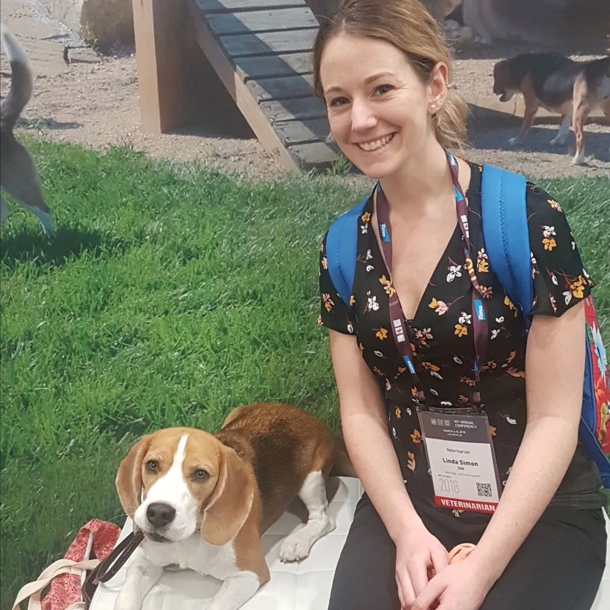 Photo of veterinarian Linda Simon sitting on a bench with a dog lying next to her. Linda is part of the Pawleaks veterinary team.